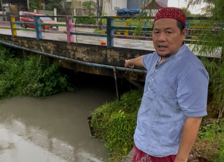 Caption foto: Ketua RT 30 Sempaja Selatan menunjukkan titik aliran anak Sungai Perjuangan yang kerap dipenuhi sampah plastik dari kawasan GOR Kadrie Oening, terutama usai hujan dan air pasang.
